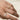 Gold band with a smooth texture on a person's finger against a neutral background