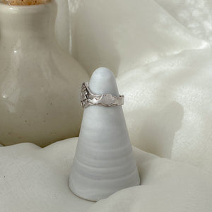Cloud detail on sterling silver ring in front of white neutral backdrop.