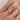 Round, bezel set diamond solitaire gold ring on a hand against a neutral background