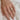 Hand wearing two diamond rings on a white fabric background; one ring is a round, diamond solitaire and the other is a curved, diamond half halo ring.