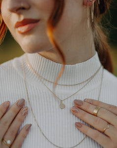 woman-wearing-white-mock-turtleneck-with-layered-gold-necklaces