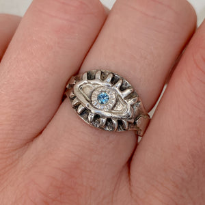 close-up of hand wearing a sterling silver ring. Eyeball ring with light blue sapphire.