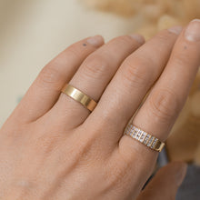 Load image into Gallery viewer, Gold band with a smooth texture on a finger with a blurred background