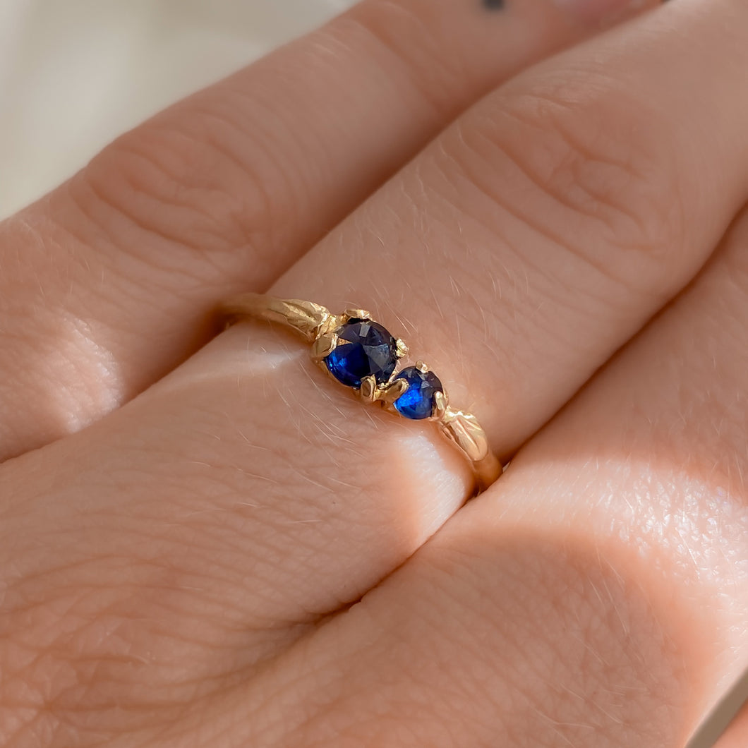 model-wearing-14k-gold-ring-with-two-dark-blue-sapphires