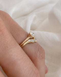 Gold, diamond ring on a finger against a soft background