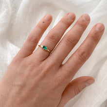 Load image into Gallery viewer, Woman wearing an oval emerald with an east to west prong setting in a 14k yellow gold solitaire ring.