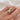 Gold ring with a marquise diamond solitaire ring on a hand against a white background