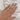 Hand wearing a gold ring with a diamond on a white fabric background