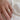 Gold ring with a diamond on a person's finger against a white fabric background