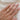 Hand wearing a gold ring with a marquise diamond solitaire on a white fabric background