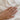 Hand wearing a gold ring with a marquise diamond solitaire on a white fabric background