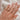 Hand wearing a gold ring with salt and pepper diamond on a white fabric background