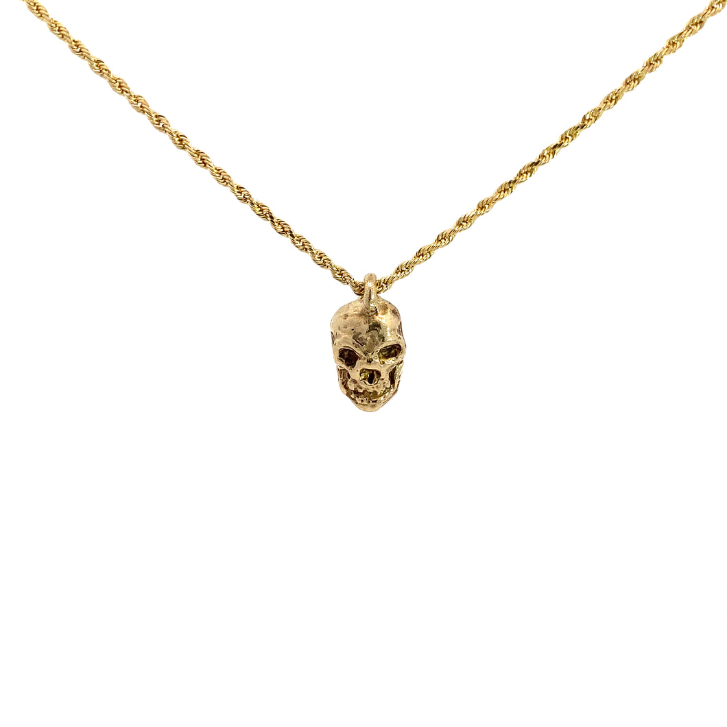 A gold skull pendant necklace with a fine gold chain.
