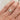 Gold ring with blue gemstones on a hand against a neutral background