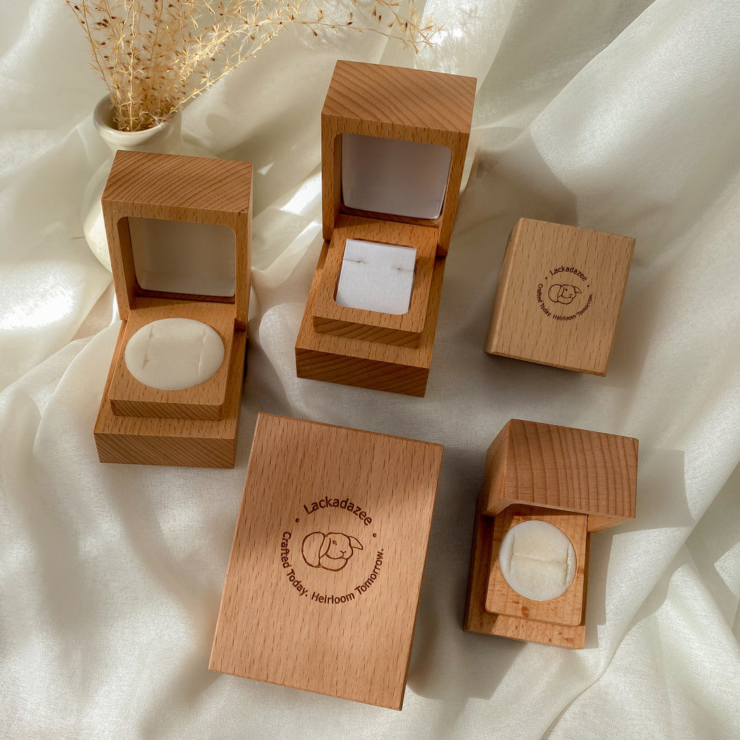 Handcrafted wooden ring boxes in various sizes, open and closed, with a velvet lining, displayed on a soft surface.