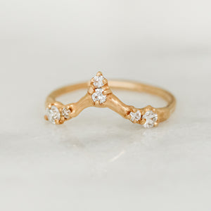 A white diamond ring with gold band, featuring multiple stones set in a pointed pattern.
