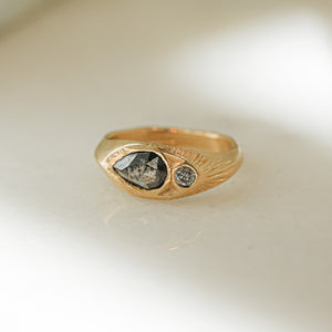 A signet ring with a salt and pepper diamond set in a hand-engraved band of recycled 14k gold, featuring a handcrafted design.