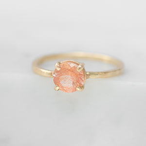 Gold ring with a pink gemstone on a light gray background