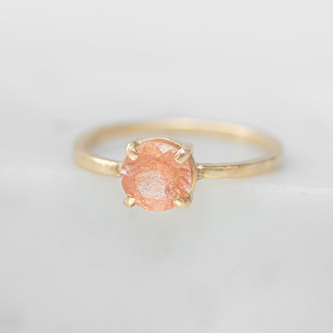 Gold ring with a pink gemstone on a light gray background