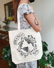 Load image into Gallery viewer, Woman holding cotton tote bag with the earth saying give a fuck on it