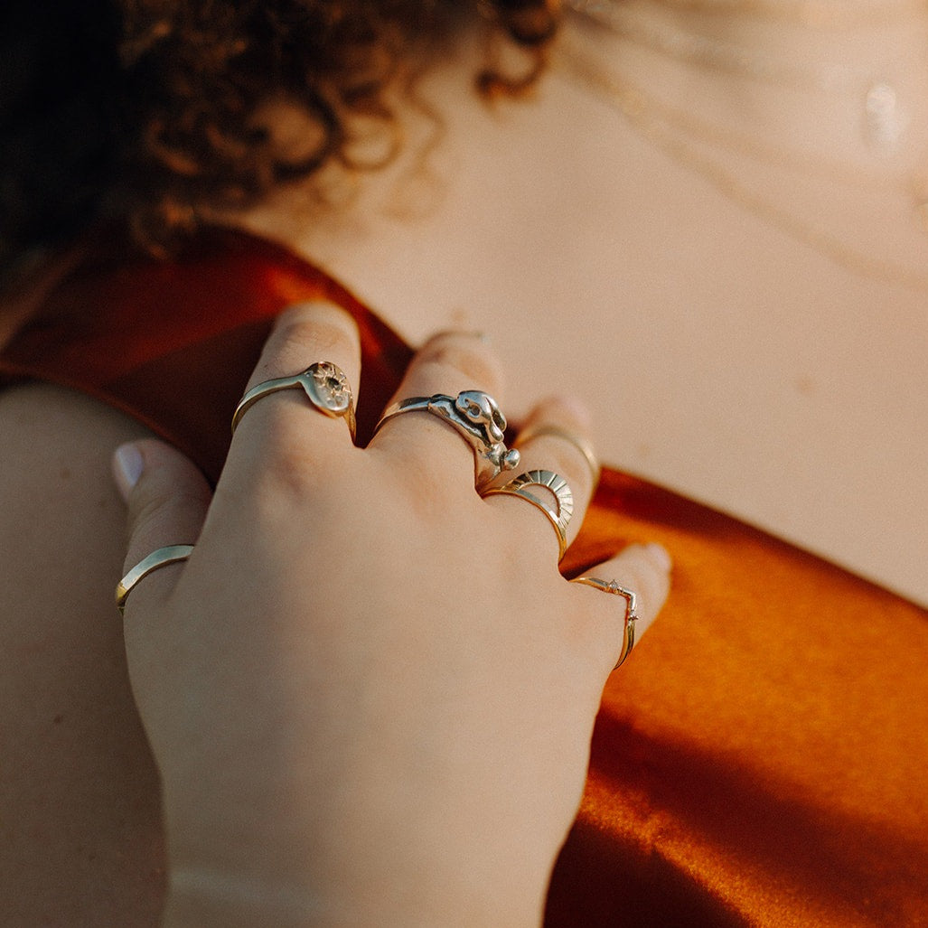 A person's hand showcasing multiple rings, including the Lackabunny Ring, with a focus on the jewelry against a warm-toned background.