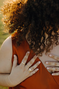 curly-haired-woman-wearing-orange-dress-wearing-gold-rings