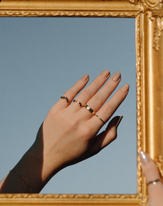 hand-towards-the-sky-wearing-black-diamond-rings-and-gold-bands