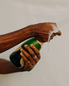 man-with-lots-of-rings-on-popping-bottle-of-champagne