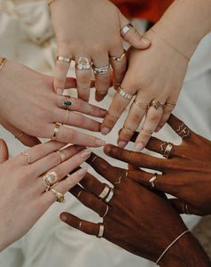 hands-in-a-circle-wearing-stacks-of-silver-and-gold-rings