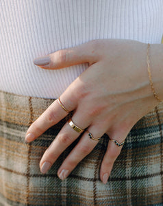 woman-wearing-gold-bands-and-black-diamond-rings