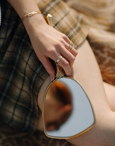 woman-holding-hand-held-mirror-wearing-gold-rings