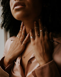 woman-wearing-stacking-rings-and-midis-in-open-silk-pink-blouse