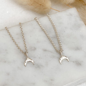 sterling-silver-crescent-moon-necklaces-lying-side-by-side-on-a-marble-surface